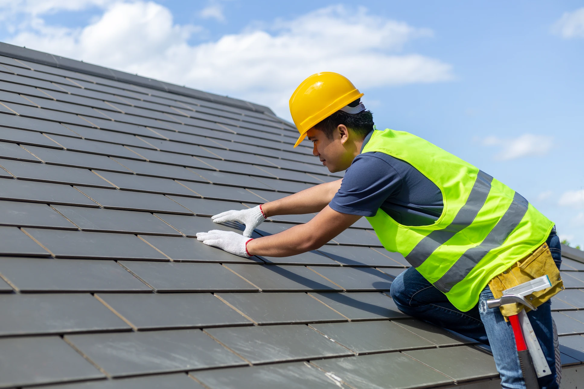 Ouvrier en équipement de sécurité installe des panneaux solaires photovoltaïques sur une toiture résidentielle par temps ensoleillé